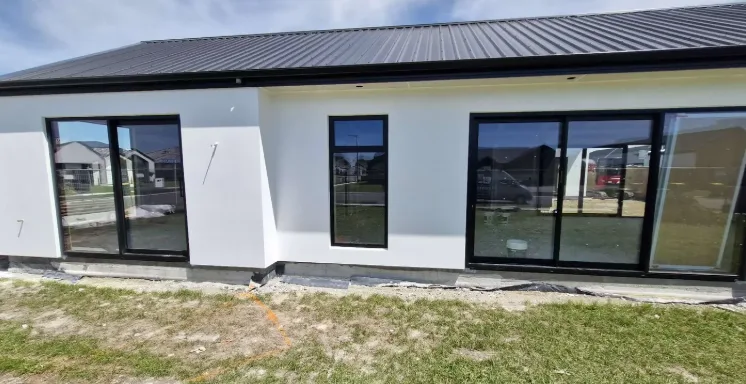 White-rendered home facade with black-framed windows and sliders