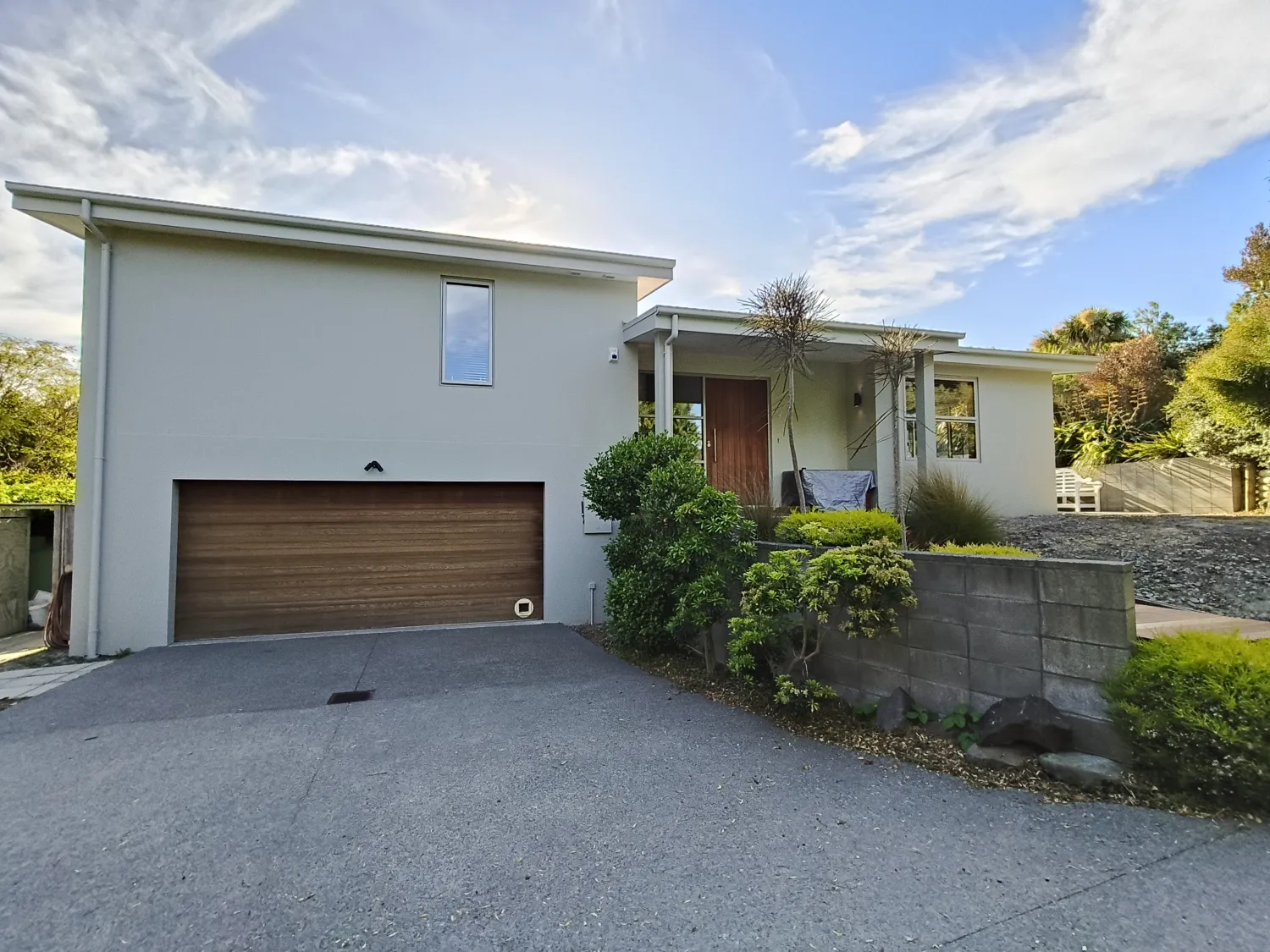 Modern two-storey render home with wood garage door and cedar entry
